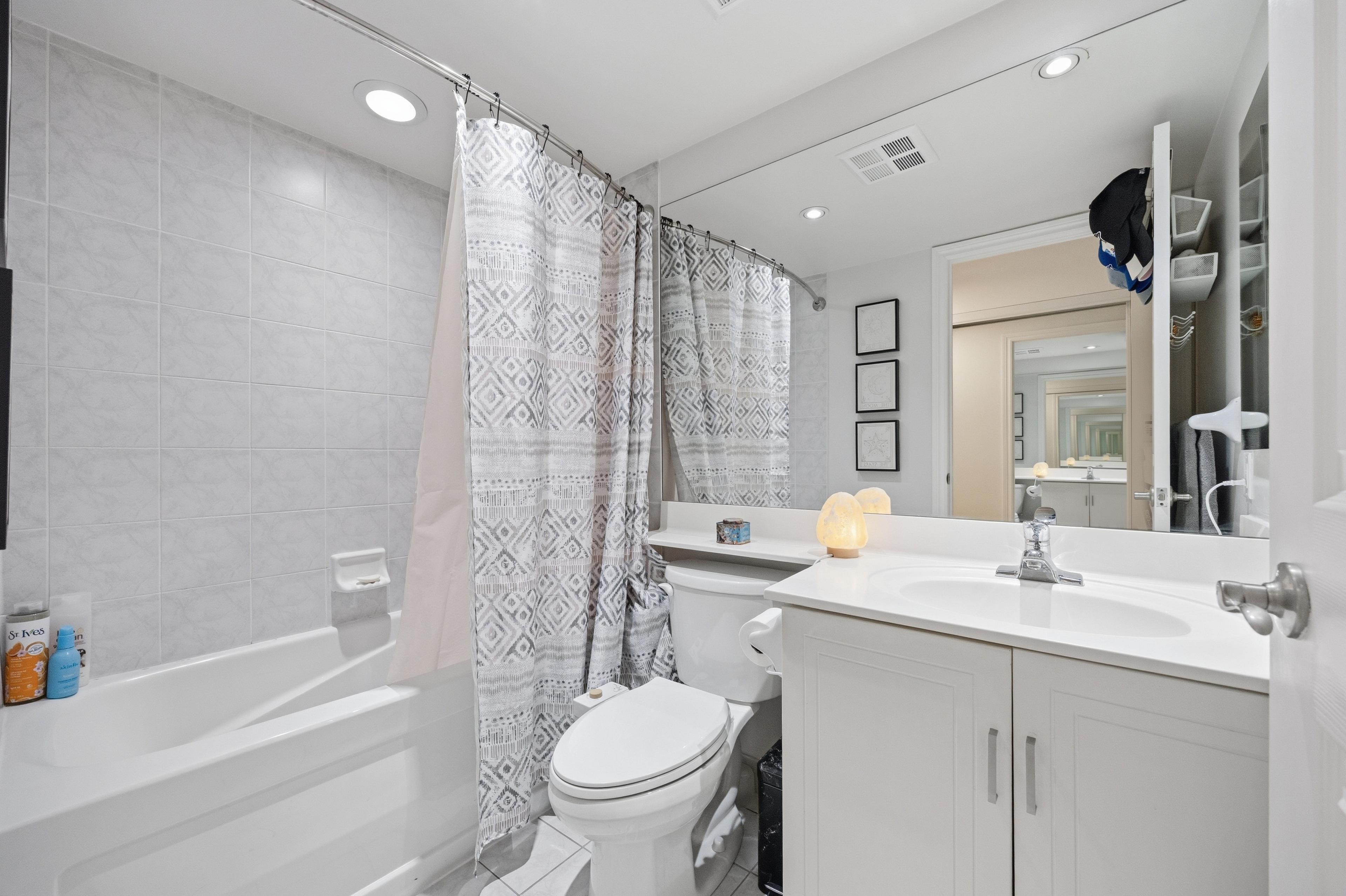 Bathroom with full tub, white vanity, and clean finishes