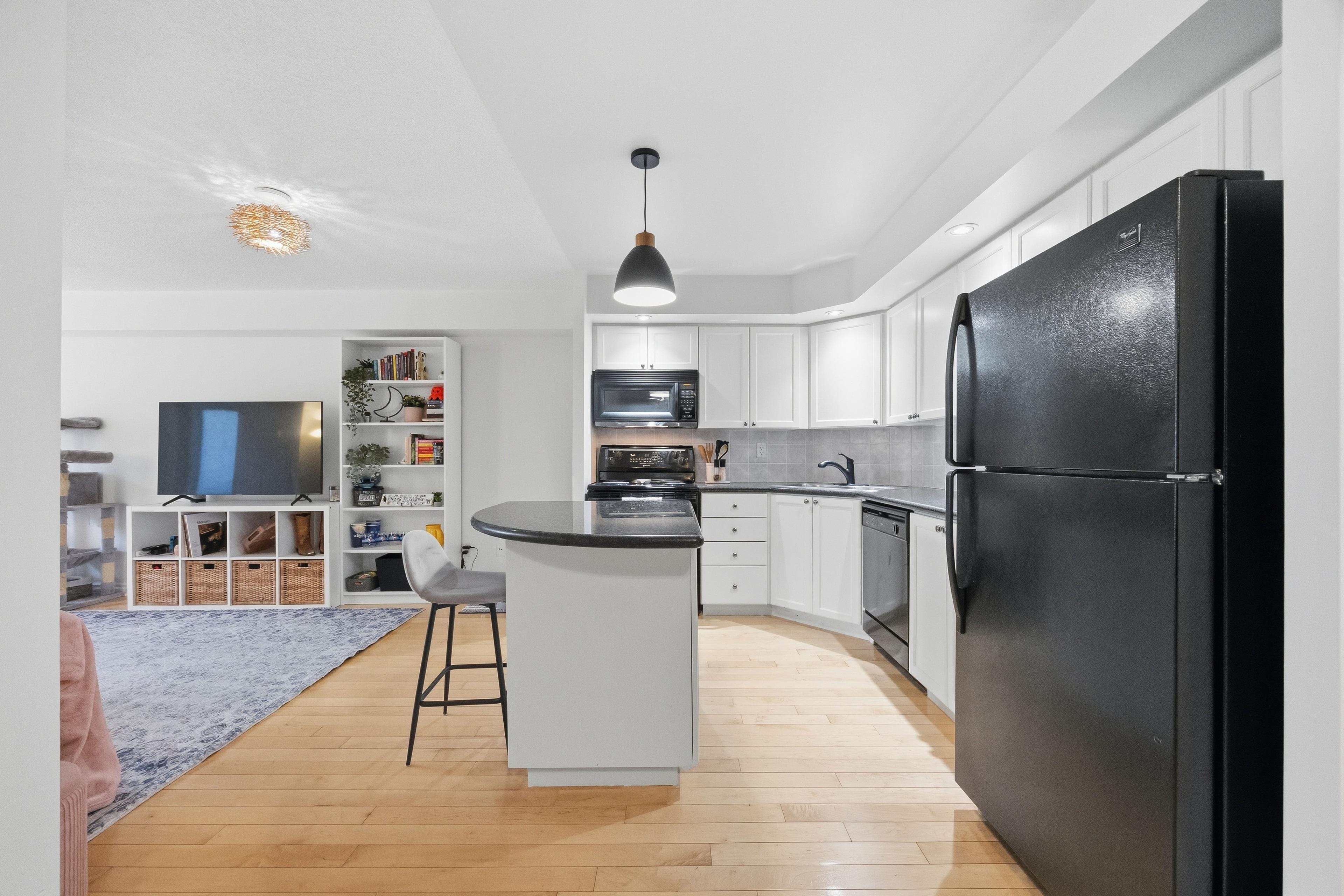 Kitchen with island, white cabinetry, and pendant light