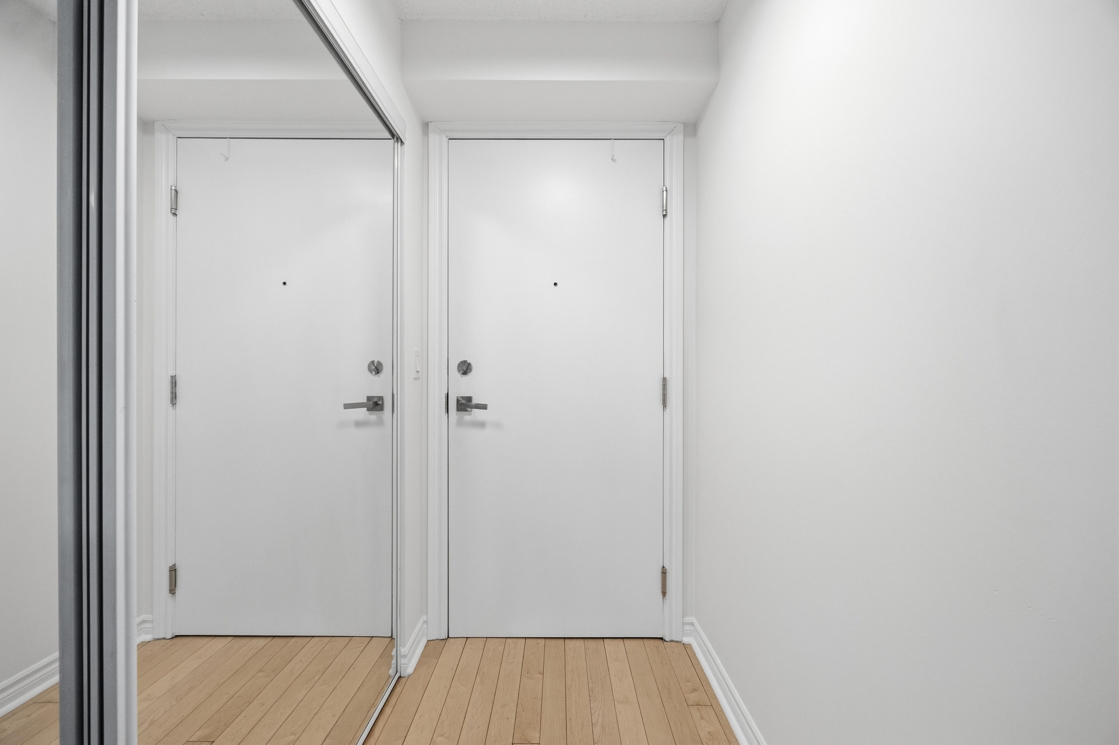 Entryway with large mirrored closet and hardwood floors