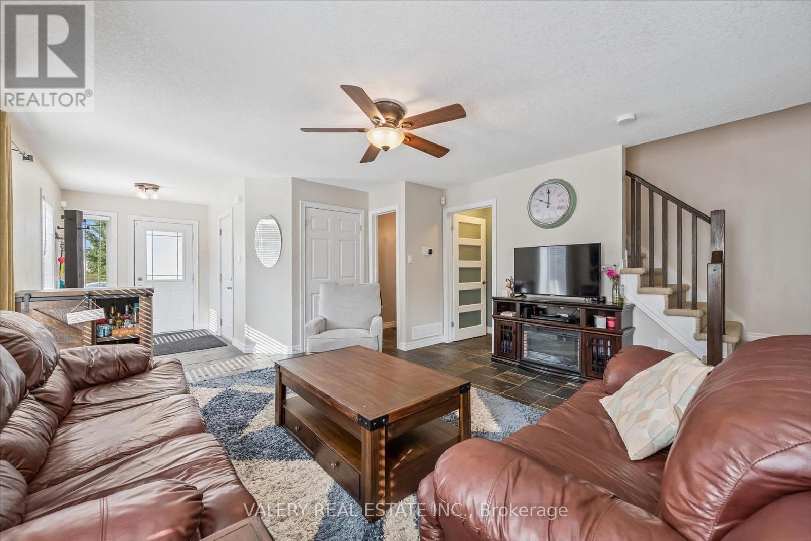 Open-concept living room with ceiling fan and staircase